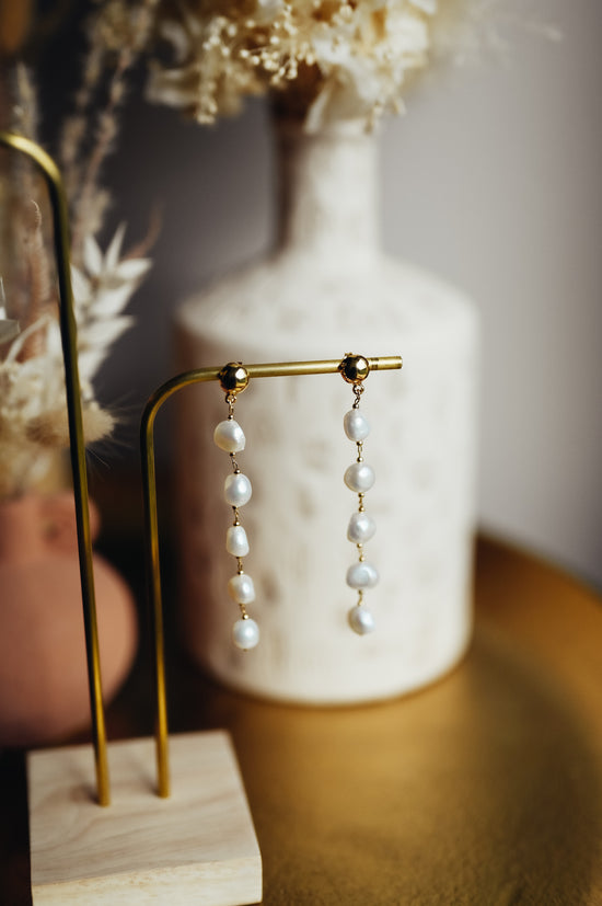 Boucles d'oreilles Émilie  Ces boucles d'oreilles délicates sont composées d'une succession de perles naturelles montées sur une chaîne plaqué-or 3 microns.   Ces boucles d’oreilles sont disponibles en clip pour les oreilles non-percées.