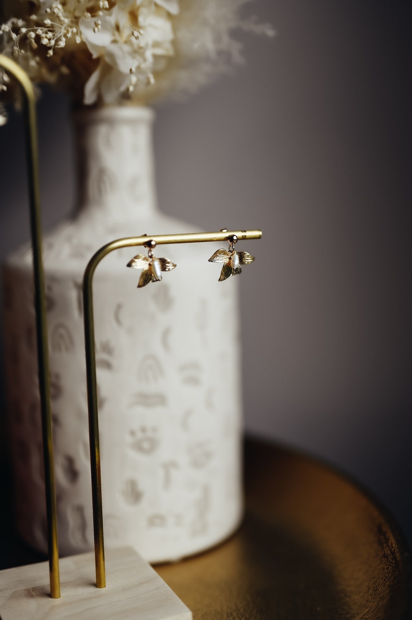 Boucles d’oreilles Flore  Ces boucles d’oreilles en forme de fleurs sont réalisées en plaqué-or 3 microns et composées d’une perle naturelle.  Elles sont idéales pour des cheveux courts ou attachés.  Ces boucles d’oreilles sont disponibles en clip pour les oreilles non-percées. 